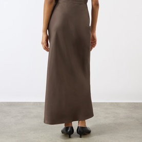 Model wearing Loulou Studio dark brown silk maxi skirt, back view, styled with black kitten heel mules.