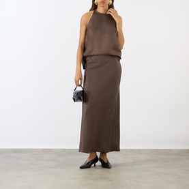 Model wearing Loulou Studio dark brown silk midi skirt, styled with matching halterneck top, carrying small black bag, with black heels.