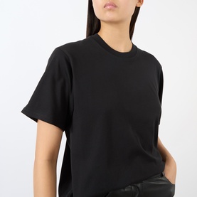 Model wearing black crew-neck oversized T-shirt with short sleeves, styled with black leather trousers