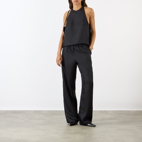 Model wearing Loulou Studio Cami Silk Cape Top in black, styled with matching black wide-leg trousers and black pointed-toe flats.