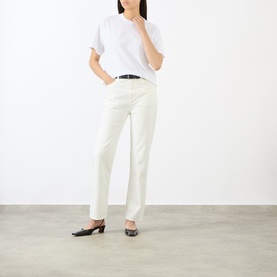 Model wearing Loulou Studio white cotton T-shirt, styled with cream straight-leg trousers, black belt and black heeled mules.