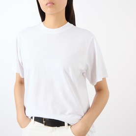 Model wearing Loulou Studio white cotton T-shirt with crew neck and short sleeves, styled with a black belt and cream trousers.