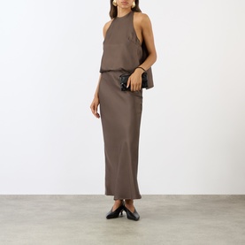 Model wearing Loulou Studio dark brown silk halterneck top, styled with matching maxi skirt, small black clutch bag and black heeled mules.
