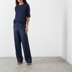 Model wearing Loulou Studio Nala Cashmere Sweater in navy, short sleeves, round neck, styled with matching wide-leg satin trousers.