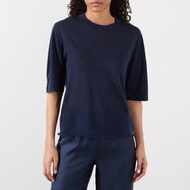 Model wearing Loulou Studio Nala Cashmere Sweater in navy, short sleeves, round neck, paired with navy trousers.