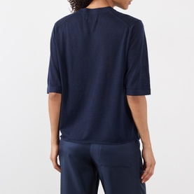 Model wearing Loulou Studio Nala Cashmere Sweater in navy, short sleeves, round neck, paired with navy trousers, rear view.