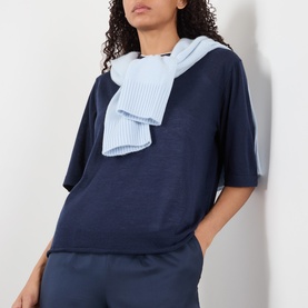 Model wearing Loulou Studio Nala Cashmere Sweater in navy, short sleeves, round neck, styled with a light blue ribbed scarf.