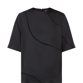 Loulou Studio black silk top with short sleeves, round neck, back zip, and curved tonal seam detailing at front
