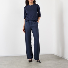 Model wearing Loulou Studio navy silk wide-leg trousers with elasticated waist, styled with a navy T-shirt and black heels.