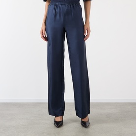 Model wearing Loulou Studio navy silk wide-leg trousers with elasticated waist, styled with black pointed heels.