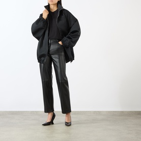 Model wearing Loulou Studio black lambskin leather trousers, styled with an oversized black jacket and black heels.