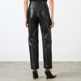 Model wearing Loulou Studio black lambskin leather trousers, rear view, styled with black pointed-heel mules.