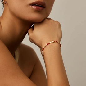 Model with Missoma bracelet in gold and red, featuring pearl and red bead detailing on wrist