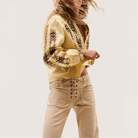 Model wearing Bash yellow embroidered blouse with floral detail, styled with beige lace-up wide-leg trousers