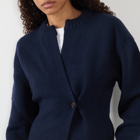 Model wearing Soeur navy merino wool cardigan, open-front style with single gold-tone button, layered over a white top.