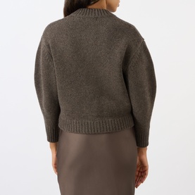 Model wearing Soeur brown merino wool cardigan, back view, with voluminous sleeves and ribbed hem, styled with a brown midi skirt.