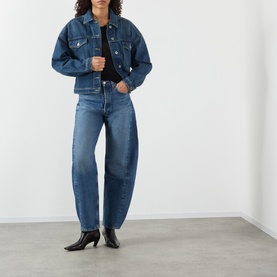 Model wearing Soeur mid blue denim jacket with matching barrel-leg jeans and black heeled ankle boots.