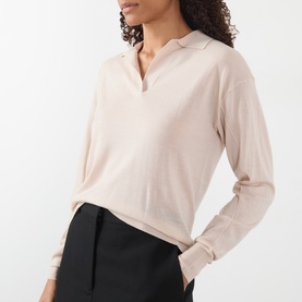 Model wearing Soeur light pink merino wool knit polo top with open V-neck collar, styled with black trousers.
