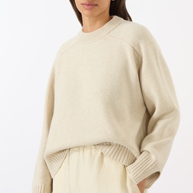 Model wearing Soeur ecru chin&eacute; merino wool crew-neck jumper with ribbed cuffs and relaxed fit, styled with matching wide-leg trousers.