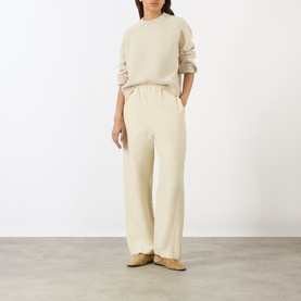 Model wearing Soeur ecru chine merino wool knit sweatshirt with wide-leg cream trousers and tan flat shoes.