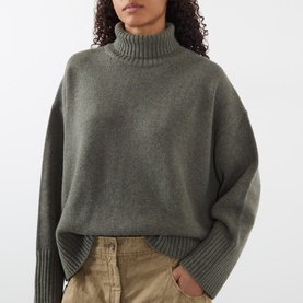 Model wearing Soeur grey merino wool turtleneck sweater with oversized fit and ribbed cuffs, styled with beige trousers