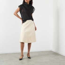 Model wearing Soeur cream viscose midi skirt, styled with black sheer sleeveless top and black ankle-strap heels.