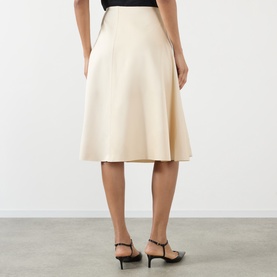 Model wearing Soeur cream viscose midi skirt with flared silhouette, styled with black strappy heels, rear view