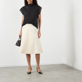 Model wearing Soeur cream viscose midi skirt, styled with black sleeveless top, small black handbag and ankle-strap flats.