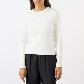 Model wearing Soeur white long-sleeve cotton T-shirt with crew neck, styled with black wide-leg trousers.