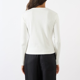 Model wearing Soeur white cotton long-sleeve T-shirt, back view, styled with black wide-leg trousers.