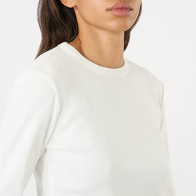 Model wearing Soeur white cotton long-sleeve crew neck T-shirt, close-up detail view showing neckline and fitted silhouette