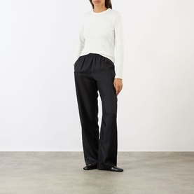Model wearing Soeur white cotton long-sleeve T-shirt, styled with black wide-leg trousers and black loafers.