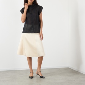 Model wearing Soeur black sleeveless sheer top with cream A-line midi skirt and black slingback heels.