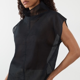 Model wearing Soeur black sleeveless top with sheer mesh panel detail and high neck, styled close-up shot.