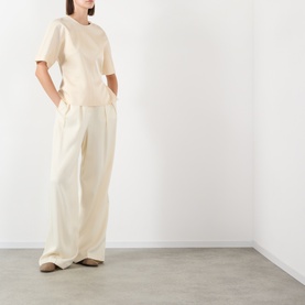 Model wearing Soeur cream viscose top with wide-leg cream trousers and tan loafers
