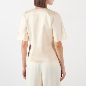 Model wearing Soeur cream short-sleeve top, back view, with relaxed fit; styled with matching wide-leg trousers.