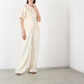 Model wearing Soeur cream viscose top with wide-leg trousers in matching cream tone, styled with taupe flat shoes.