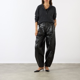 Model wearing Soeur black lambskin leather trousers with relaxed tapered fit, styled with grey knit polo and black kitten heel pumps.