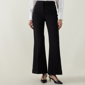 Model wearing Ted Baker black flared trousers, styled with a white shirt and black slingback heels.