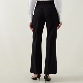Model wearing Ted Baker black wide-leg trousers, rear view, styled with a white shirt and black heels.