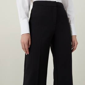 Model wearing Ted Baker black wide-leg cropped trousers with high waist, styled with a white long-sleeve top.