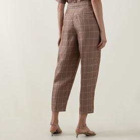 Model wearing Ted Baker beige checked tailored trousers, styled with nude strappy heeled mules, rear view.
