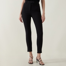 Model wearing Ted Baker black slim-leg trousers with high waist, styled with black strappy heeled sandals.