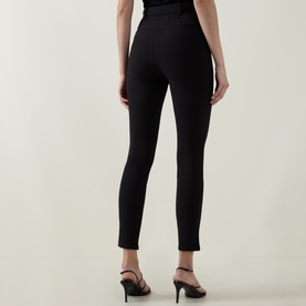 Model wearing Ted Baker black slim-leg trousers, rear view, styled with black strappy heeled sandals.