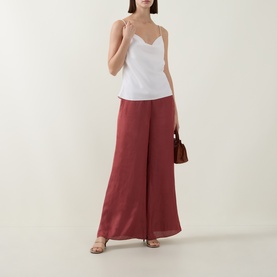 Model wearing Ted Baker Burnt Red wide-leg trousers, styled with a white cami top, strappy sandals and brown bag.