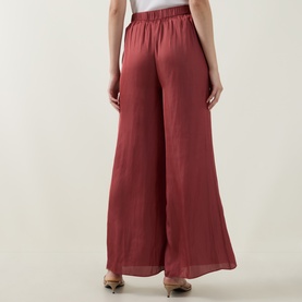 Model wearing Ted Baker Burnt Red wide-leg trousers with elasticated waist, styled with nude heeled sandals, back view.