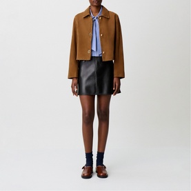 Model wearing Claude Pierlot cropped camel wool jacket with blue stripe shirt, black leather mini skirt and brown loafers