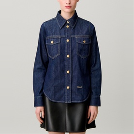 Model wearing Claude Pierlot blue denim shirt with gold buttons and chest pockets, styled with a black leather mini skirt
