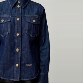 Claude Pierlot blue denim shirt with gold-tone buttons, twin chest pockets and contrast stitching detail, close-up view