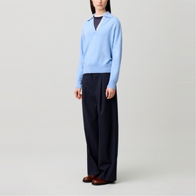 Model wearing Claude Pierlot Logo Polo Sweater in sky blue with navy wide-leg trousers and brown loafers.